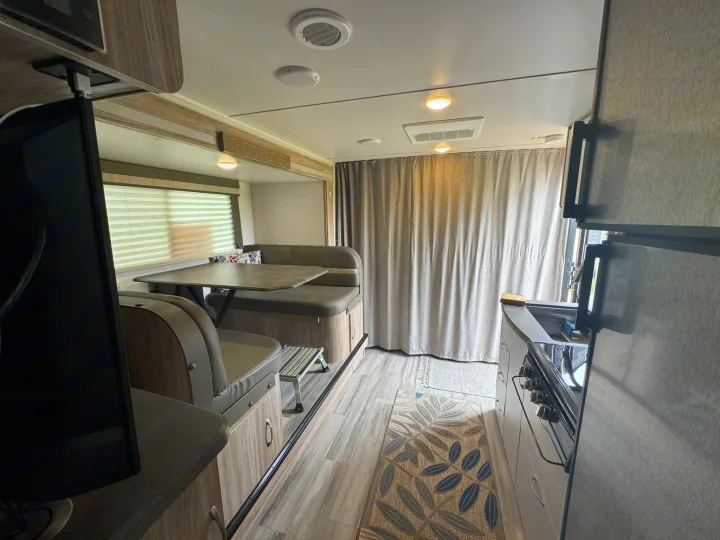 Bright RV rental interior with dinette, kitchen, and TV. Ideal for comfortable travel and adventures.. Minnie Micro Minnie 2021