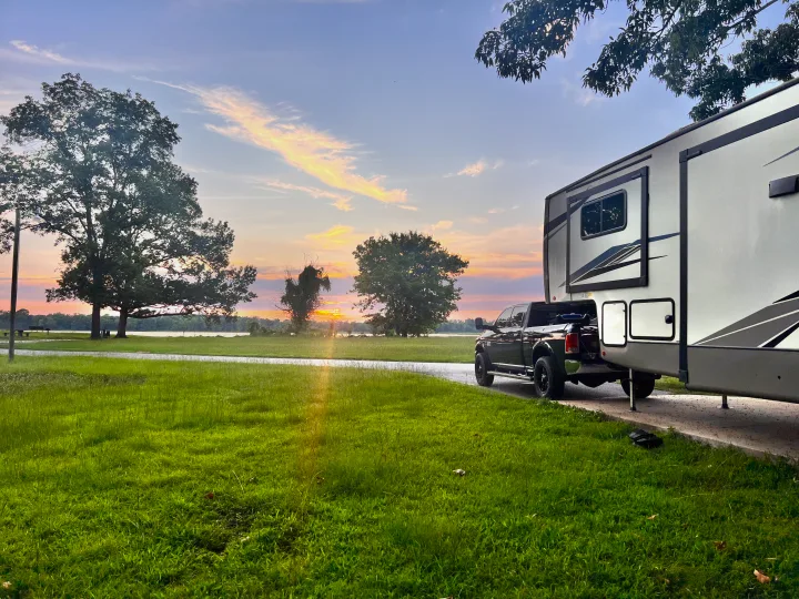 Sunset view: RV rental and truck parked by a peaceful lake, perfect for camping trips.. Forest River Salem Hemisphere 2022