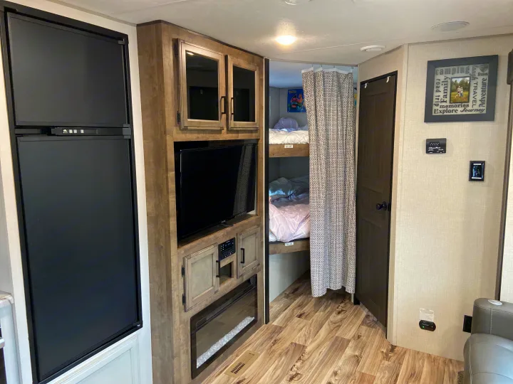 This RV rental features a cozy interior with a kitchen fridge, entertainment center, and bunk beds. Perfect for family camping!. Venture Sport Trek 2021