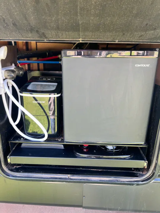RV rental convenience: outdoor kitchen with Contoure ice maker, mini fridge, and pull-out stove. Ready for camping adventures!. Forest River Cherokee 2020