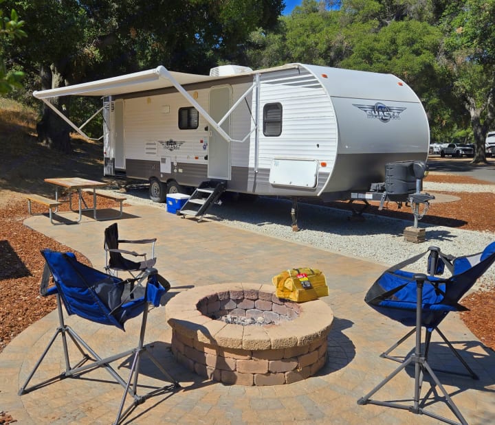 Enjoy your RV rental! This modern travel trailer campsite features a cozy fire pit, picnic table, and outdoor seating.. Forest River Shasta 2021