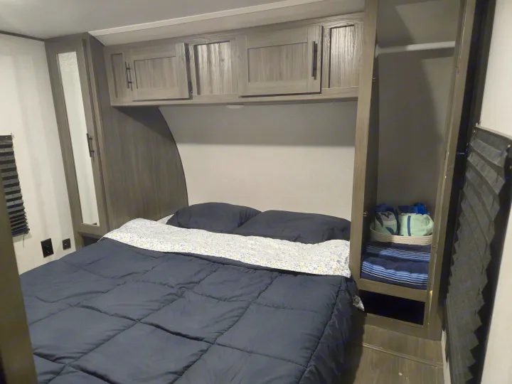 Experience comfortable sleeping in this RV rental bedroom, complete with a cozy bed, ample cabinets, and built-in storage.. Forest River Shasta 2021