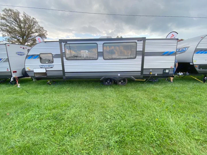 Side view of a Salem travel trailer, a great option for RV rental & camping. Parked on grass under a cloudy sky.. Forest River Salem Cruise Lite 2022