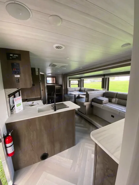 Bright RV rental interior showcasing a modern kitchen island & spacious living area with large windows and light wood floors.. Forest River Salem Cruise Lite 2022