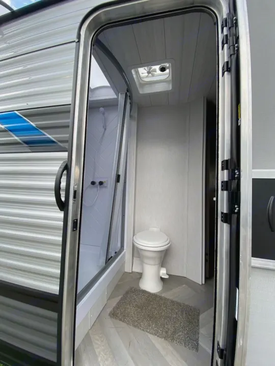 Inside an RV rental bathroom: features a compact shower stall, toilet, and ceiling fan for comfort on the road.. Forest River Salem Cruise Lite 2022