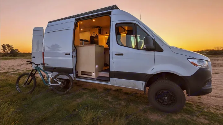 Cozy Sprinter rv rental van, open to show its interior, with a mountain bike outside at sunset. Ready for adventure!. Mercedes-Benz Sprinter 2019