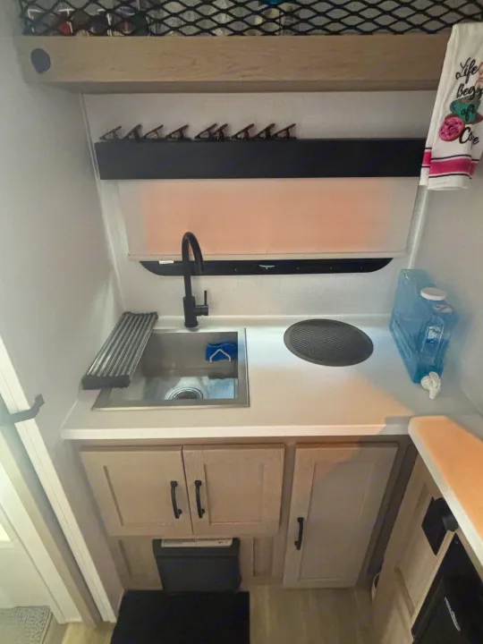 This compact RV rental kitchen features a sink, cooktop, and clever storage, perfect for your adventures.. Forest River Flagstaff E-Pro 2024