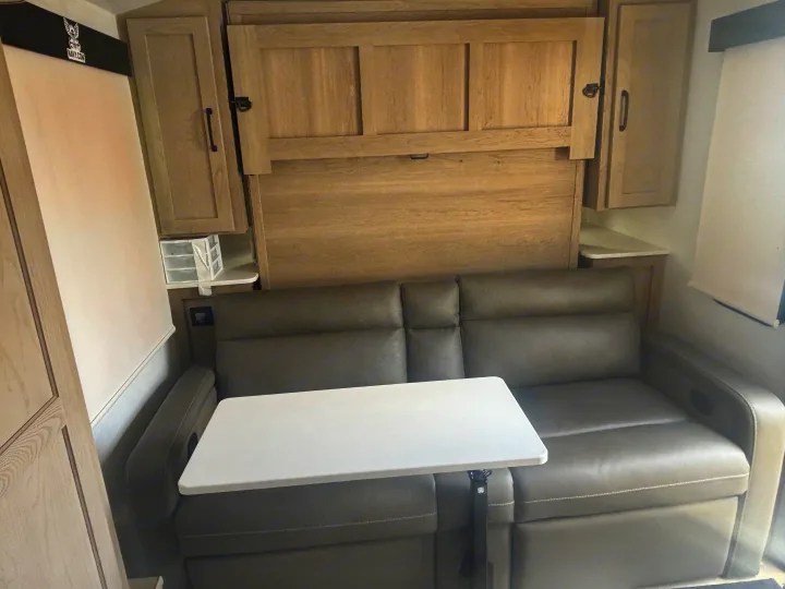 Comfortable RV rental interior featuring a versatile sofa, fold-up murphy bed, and adjustable table.. Forest River Flagstaff E-Pro 2024