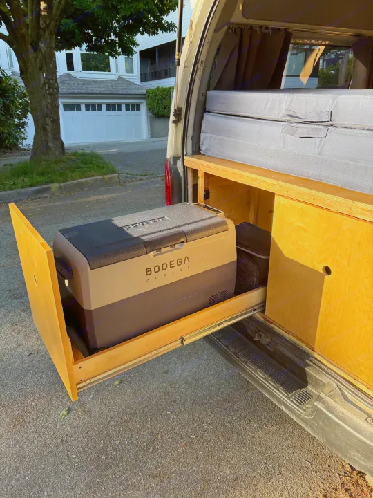 Custom camper van conversion with a slide-out Bodega cooler, ideal for an RV rental adventure. Efficient interior design.. Toyota Hiace 2006