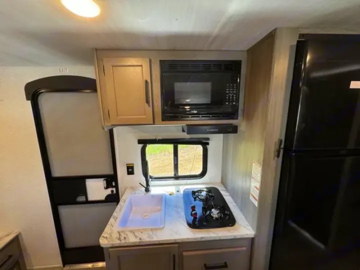 This RV rental offers a well-equipped kitchen with a sink, two-burner stove, microwave, and large refrigerator.. Keystone RV Hideout Sport 2024