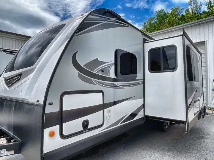 Modern travel trailer RV rental with extended slide-out, parked outdoors on asphalt.. Jayco White Hawk 2019