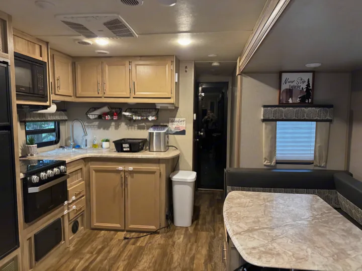 A cozy RV rental living space, showing a well-appointed kitchen with stove & sink, and a comfortable dinette table.. Coachmen Catalina 2021