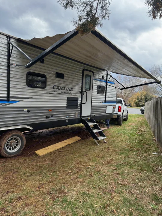 This RV rental travel trailer is parked with its awning extended, featuring a side door and steps for easy access.. Coachmen Catalina 2021