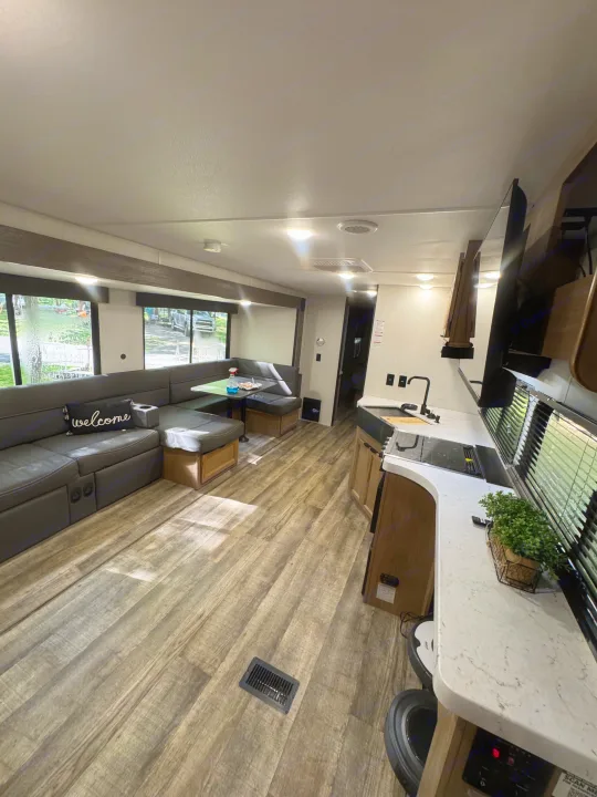 Bright RV rental interior showcasing a U-shaped sofa, dinette, and well-equipped kitchen. Perfect for comfortable travel.. Forest River Cherokee Grey Wolf 2024