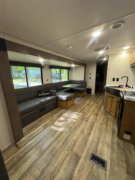 Spacious RV rental interior featuring a modern living area with dining booth and a compact kitchen.. Forest River Cherokee Grey Wolf 2024