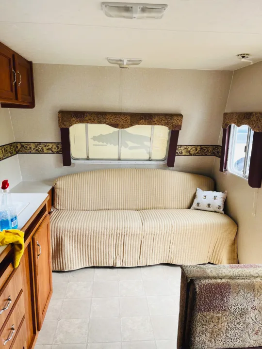 Cozy RV rental interior: beige sofa, wood cabinets, and large windows. Ready for adventure!. Dutchmen Rainier 2006