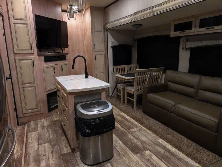 Modern RV rental interior featuring a kitchen island, dining area with table and chairs, and a comfy sofa in the living space.. Forest River Sandpiper 2022