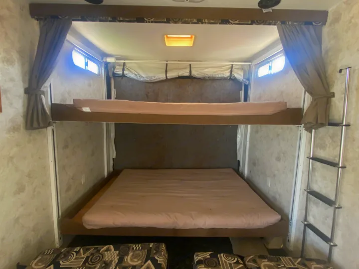 RV rental interior featuring two comfortable bunk beds with mattresses and a ladder for the top bunk.. Eclipse Recreational Vehicles Attitude 2006