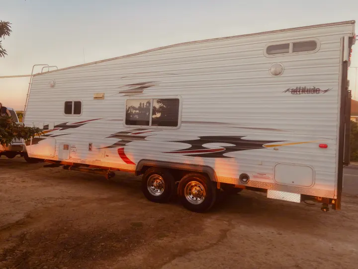 Spacious white toy hauler RV with graphics, ideal for your next RV rental adventure under a warm sky.. Eclipse Recreational Vehicles Attitude 2006