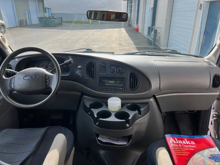 Inside an RV rental: a Ford van dashboard, steering wheel, and an Alaska map for road trip planning.. Ford Econolline 250s 2006