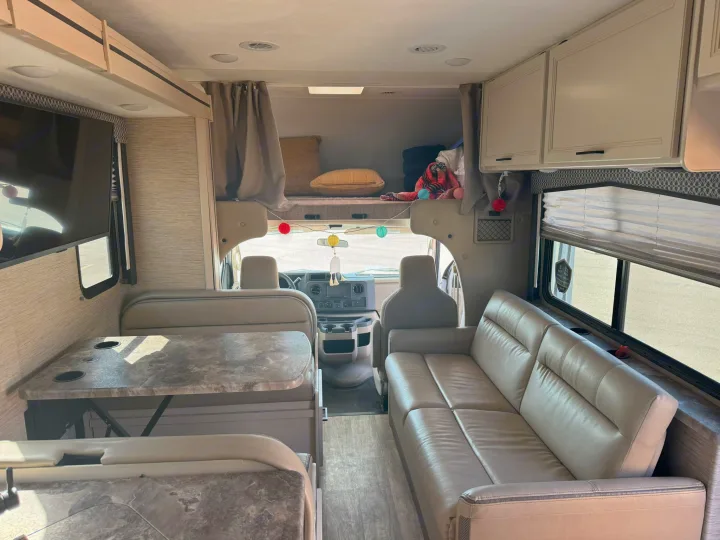 Spacious RV rental interior featuring a dinette, comfortable sofa, and cozy overhead bunk.. Thor Chateau 2023