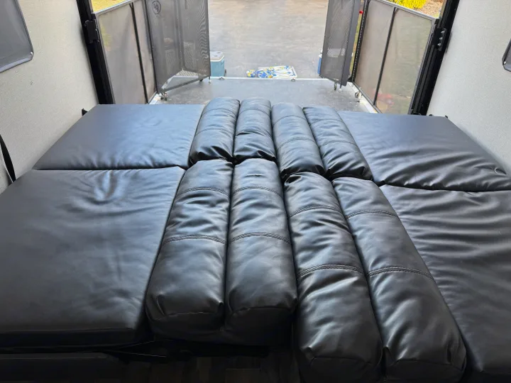 RV rental interior: Plush black convertible seating/bed, with an open rear ramp and mesh screen doors.. Coachmen Catalina 2021