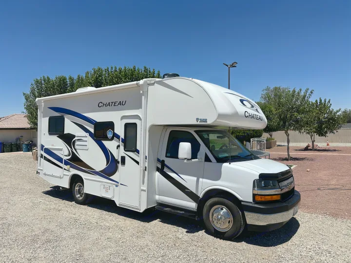 White Thor Chateau Class C RV parked on gravel under a clear sky. Book this rv rental for your next road trip adventure!. Thor Chateau 2022