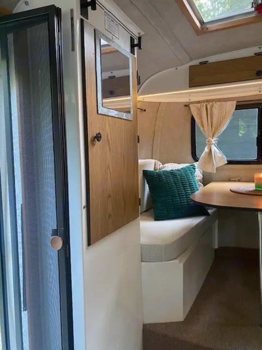Experience a cozy **RV rental**: compact interior with bench seating, a small table, and a screen door for ventilation.. Scamp Scamp Trailer 1999