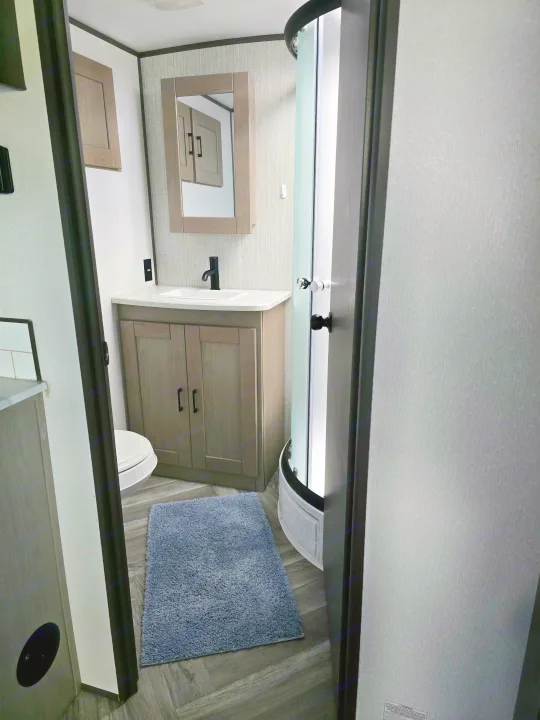 Modern RV rental bathroom: vanity, sink, toilet, and curved shower. Efficient design for travel.. Cruiser RV Shadow Cruiser 2021
