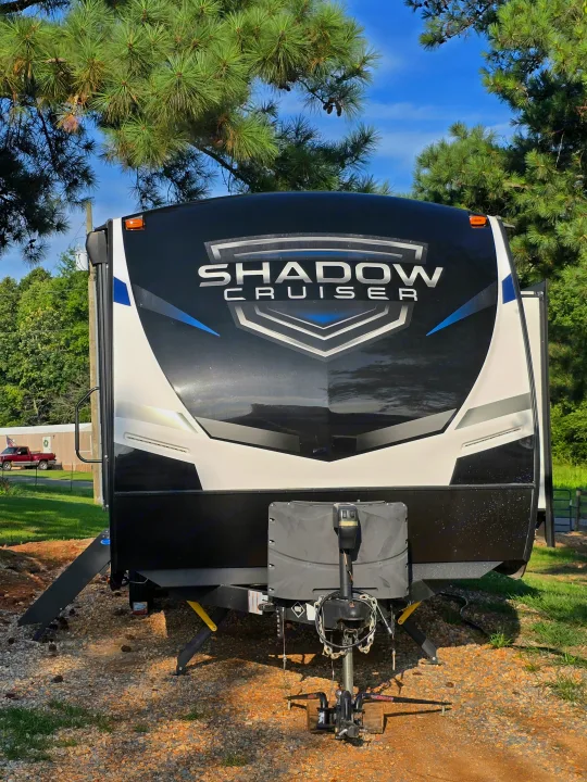 Full front view of a black and white "Shadow Cruiser" travel trailer, set for an RV rental trip, parked on gravel.. Cruiser RV Shadow Cruiser 2021