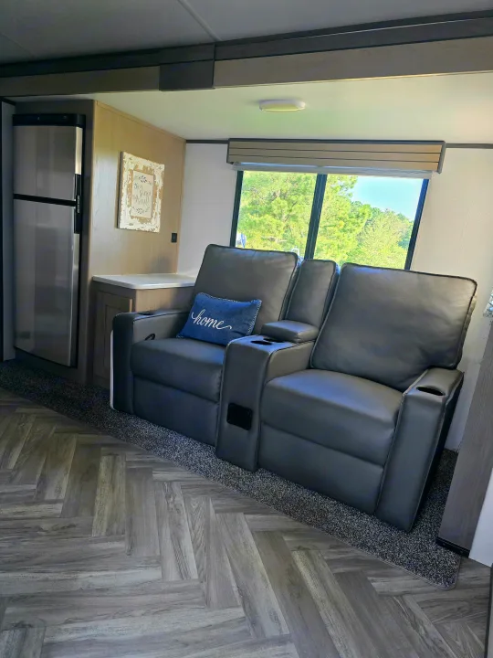 Comfortable RV rental interior with grey recliners, large window views, a fridge, and herringbone flooring.. Cruiser RV Shadow Cruiser 2021