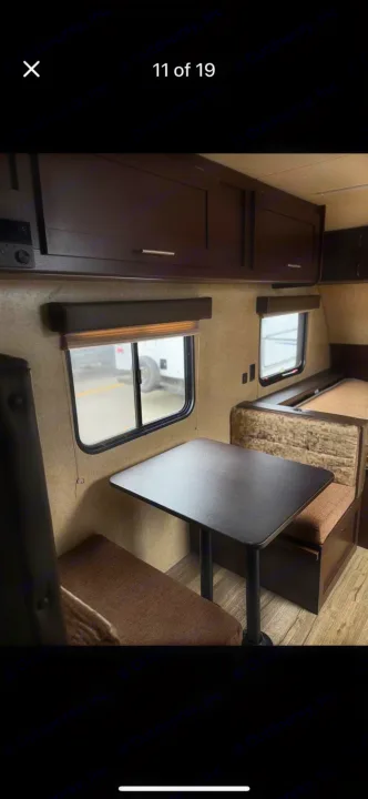 Explore this RV rental's inviting dinette area with dark cabinets, window views, and cozy benches for comfortable RV travel.. Forest River Cherokee Wolf Pup Cascade 2017
