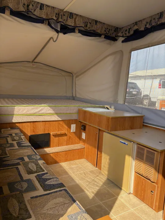 Explore this cozy pop-up RV rental interior with a bed, kitchenette, and dinette, perfect for your next road trip.. Jayco Jay Series 2006