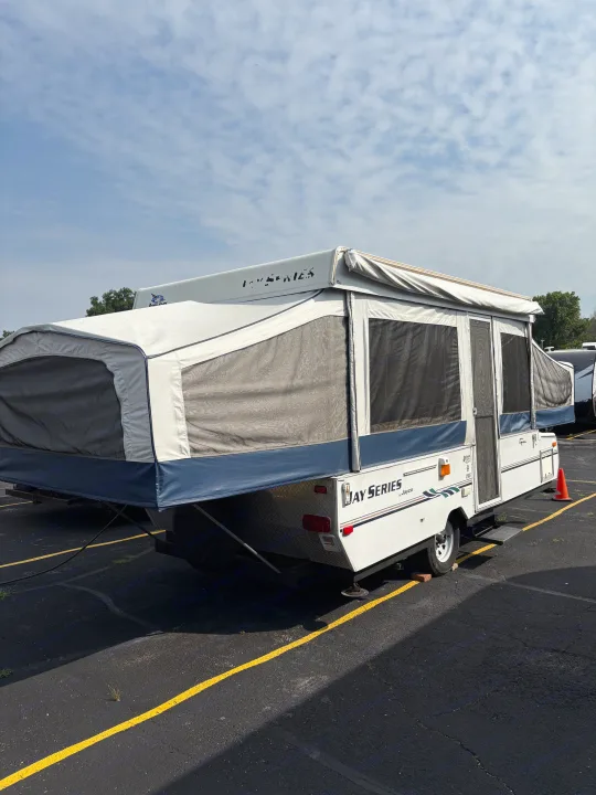 An expanded white and blue Jayco Jay Series pop-up camper in a parking lot, ideal for your next rv rental trip.. Jayco Jay Series 2006