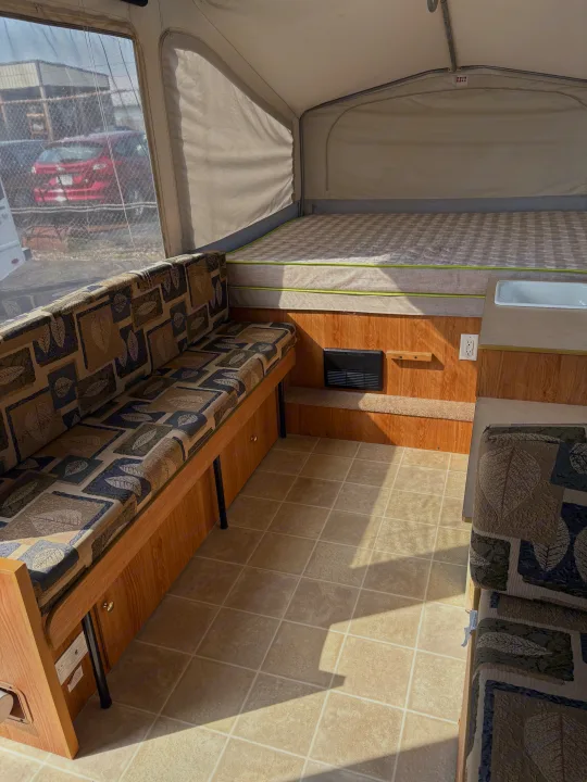 RV rental interior: comfy bed, patterned dinette, and small sink. Sun streams onto the tiled floor.. Jayco Jay Series 2006