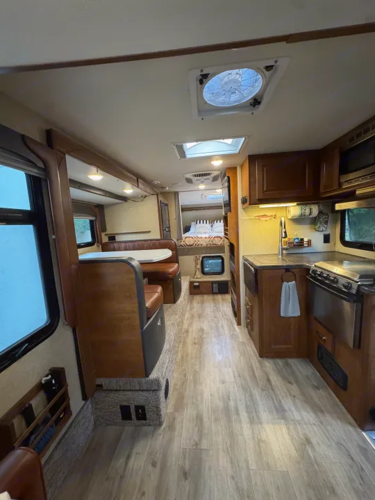 Interior of an RV rental: a spacious camper with a full kitchen, dining booth, and cozy bedroom. Ideal for travel.. Lance 1172 2017