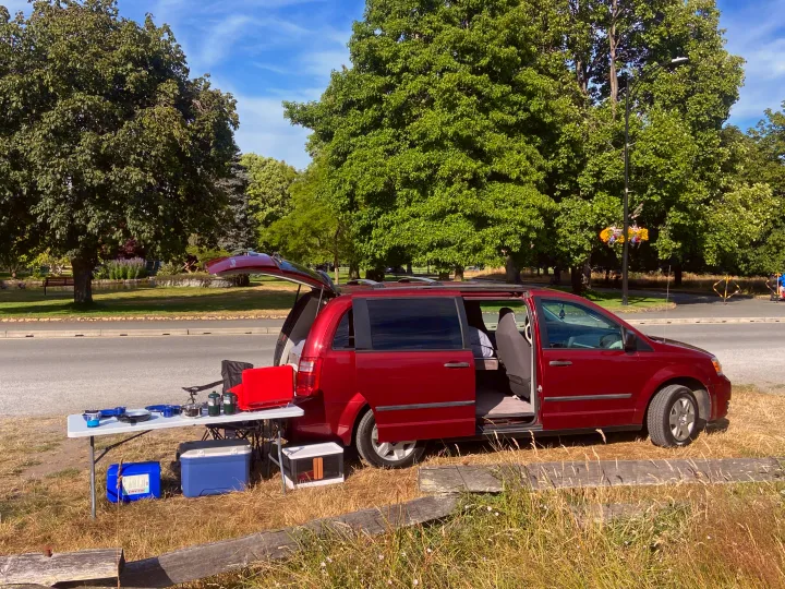 Minivan converted for camping, featuring an outdoor kitchen setup. Perfect RV rental for van life adventures!. Dodge Grand Caravan 2010
