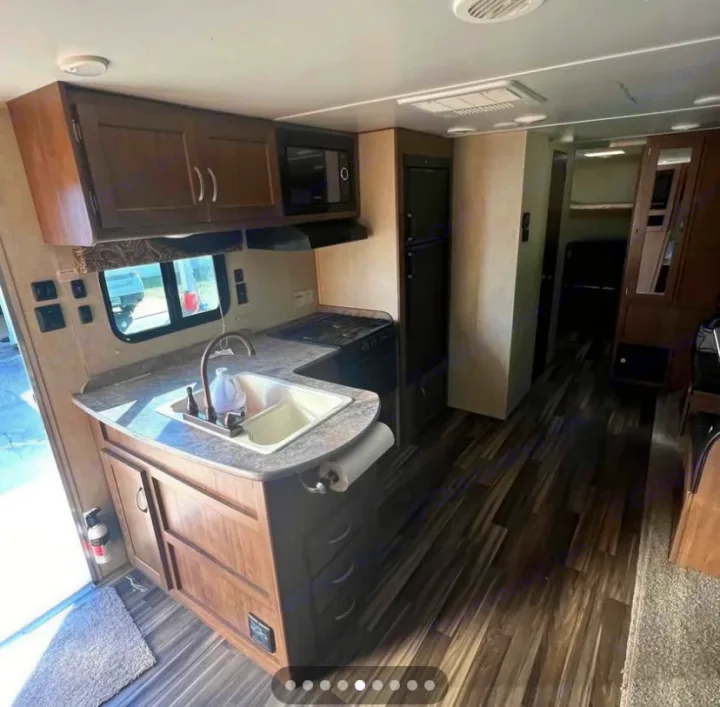 RV rental interior: full kitchen with sink, stove, microwave, and refrigerator, leading to main living/sleeping areas.. Gulf Stream Conquest 2017
