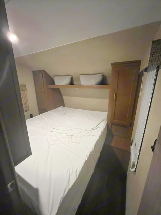 RV rental interior: cozy bedroom with a white bed, wood cabinets, and overhead storage baskets.. Gulf Stream Conquest 2017