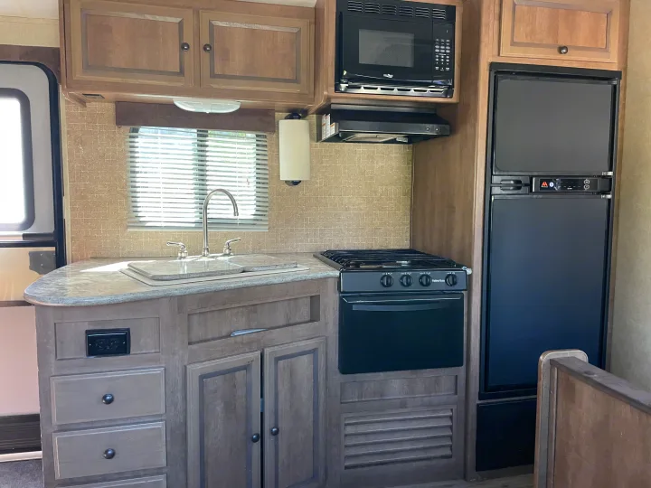 This RV rental offers a well-equipped kitchen with microwave, oven, sink, fridge, and ample storage.. Cruiser RV Radiance 2015