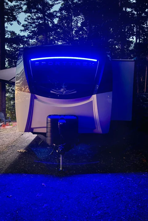 A SportTrek RV rental, brightly lit by blue LEDs on its front and the ground, sets a cool night camping scene.. Venture Rv SPORTTREK TOURING EDITION 2025