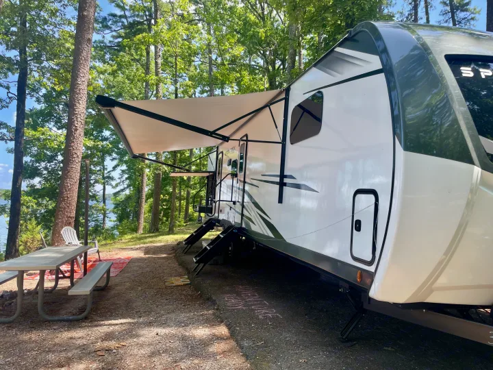 Lakeside RV rental camping: White travel trailer with awning, picnic table, and scenic nature views.. Venture Rv SPORTTREK TOURING EDITION 2025
