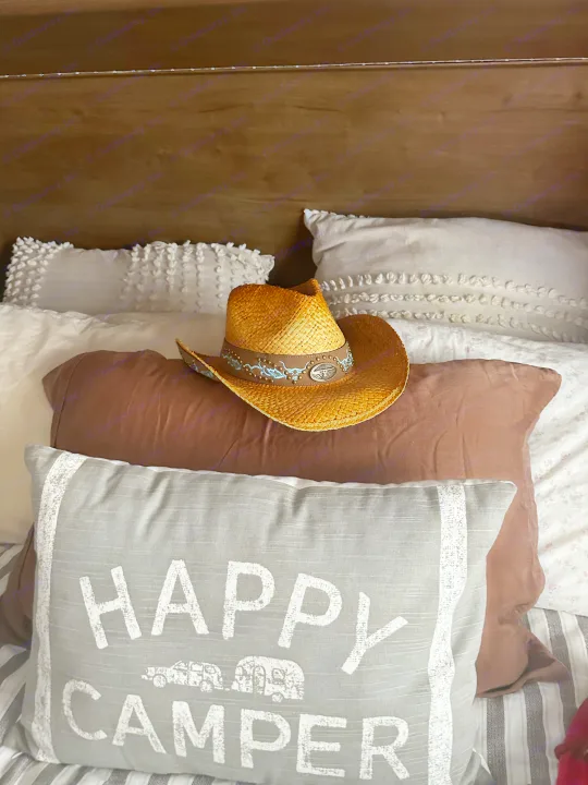 Ready for an RV rental trip? This cozy bed with a 'Happy Camper' pillow & cowboy hat sets the scene.. Keystone RV Cougar 2019