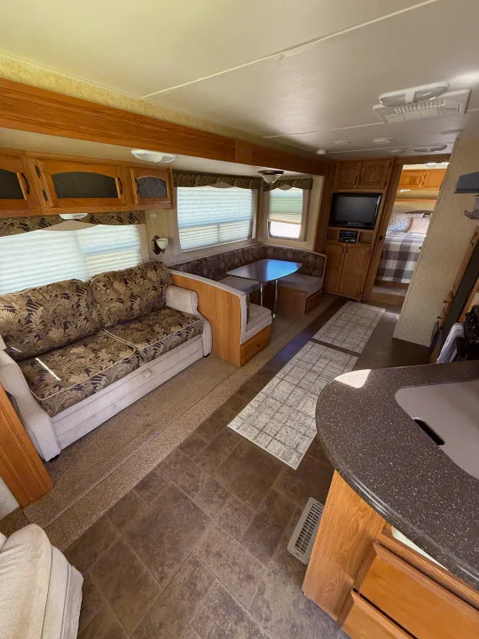 Spacious RV rental interior with a sofa, dinette, kitchen area, and a glimpse of the bedroom.. Denali Denali Trailer 2011