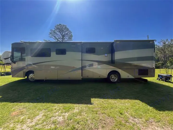 Spacious RV rental motorhome on grass, its slide-outs extended. A generator sits nearby. Perfect for your next outdoor journey.. Itasca Horizon 2002