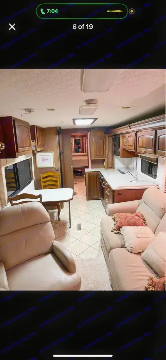 Spacious RV rental interior featuring a living area, kitchen, dining table, and bedroom in the distance.. Itasca Horizon 2002
