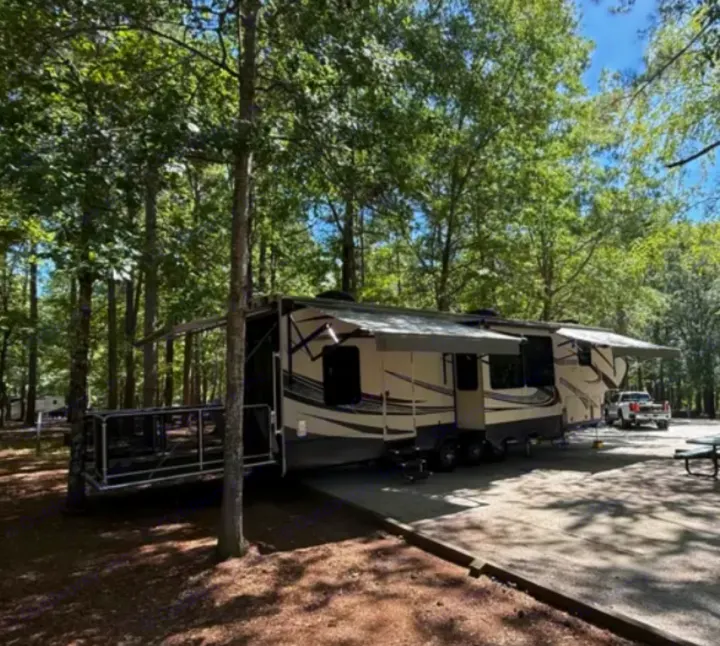 This large, light-colored RV rental with extended awnings & a rear deck is set in a peaceful, shaded campground site.. Grand Design Momentum Toy Hauler 2015