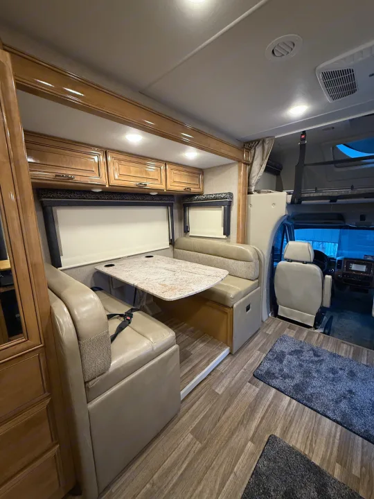 Spacious RV rental interior featuring a cozy dinette, overhead storage, and wood-look flooring for comfortable travel.. Thor Quantum 2018