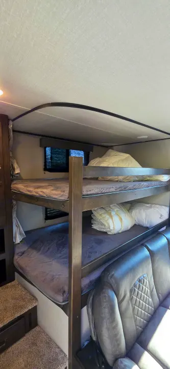 Cozy RV rental interior with bunk beds and a comfortable gray couch, perfect for family travel.. Grand Design Transcend Xplor 2021
