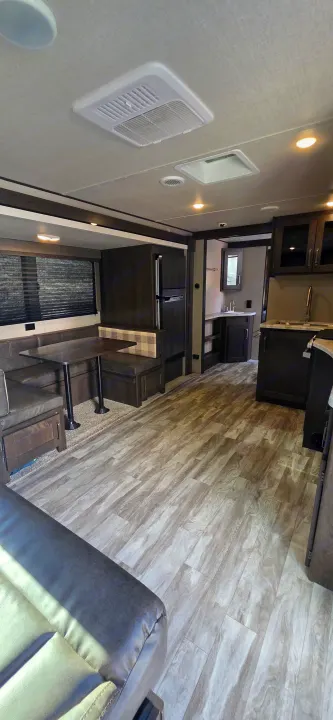 Clean, spacious RV rental interior: dinette, full kitchen, comfy living area, and modern wood-look floors.. Grand Design Transcend Xplor 2021